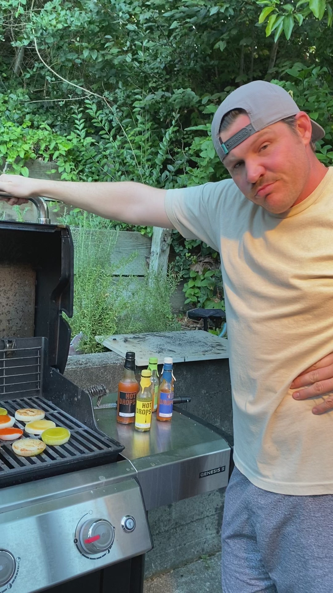 Load video: Pictured here, the founder opening a BBQ with hot sauce in background and burgers on the BBQ